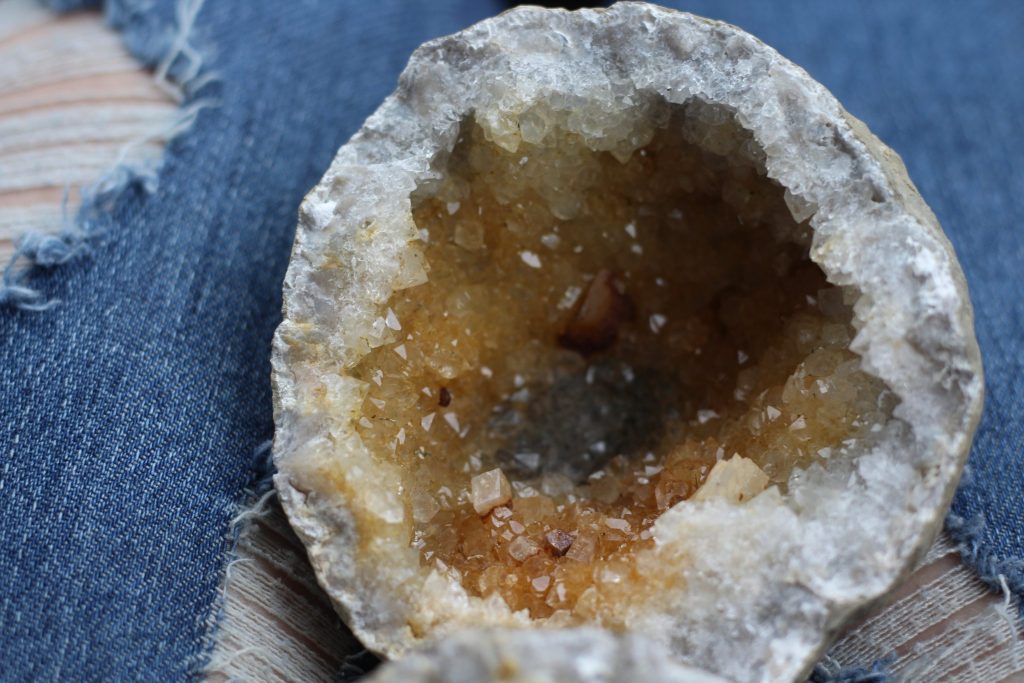 Half of a keokuk geode with gold coloring and a sprinkling of pyrite at the bottom